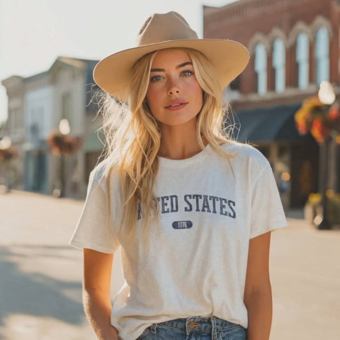 Video of a man wearing the Ash t-shirt with 'UNITED STATES 1776' in navy collegiate text.