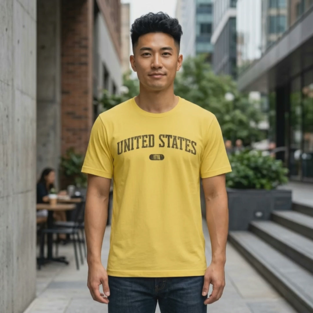 Video of a man wearing the Maize Yellow t-shirt with 'UNITED STATES 1776' in black collegiate text.