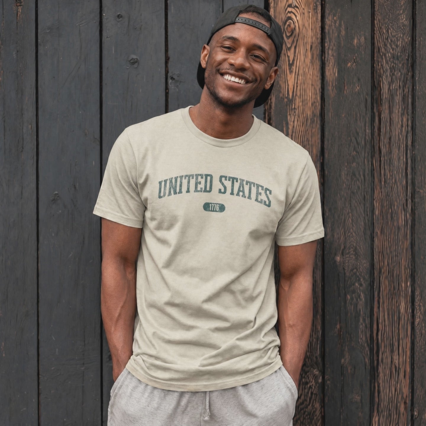 Video of a man wearing the Heather Prism Neutral t-shirt with 'UNITED STATES 1776' in transformative teal collegiate text.