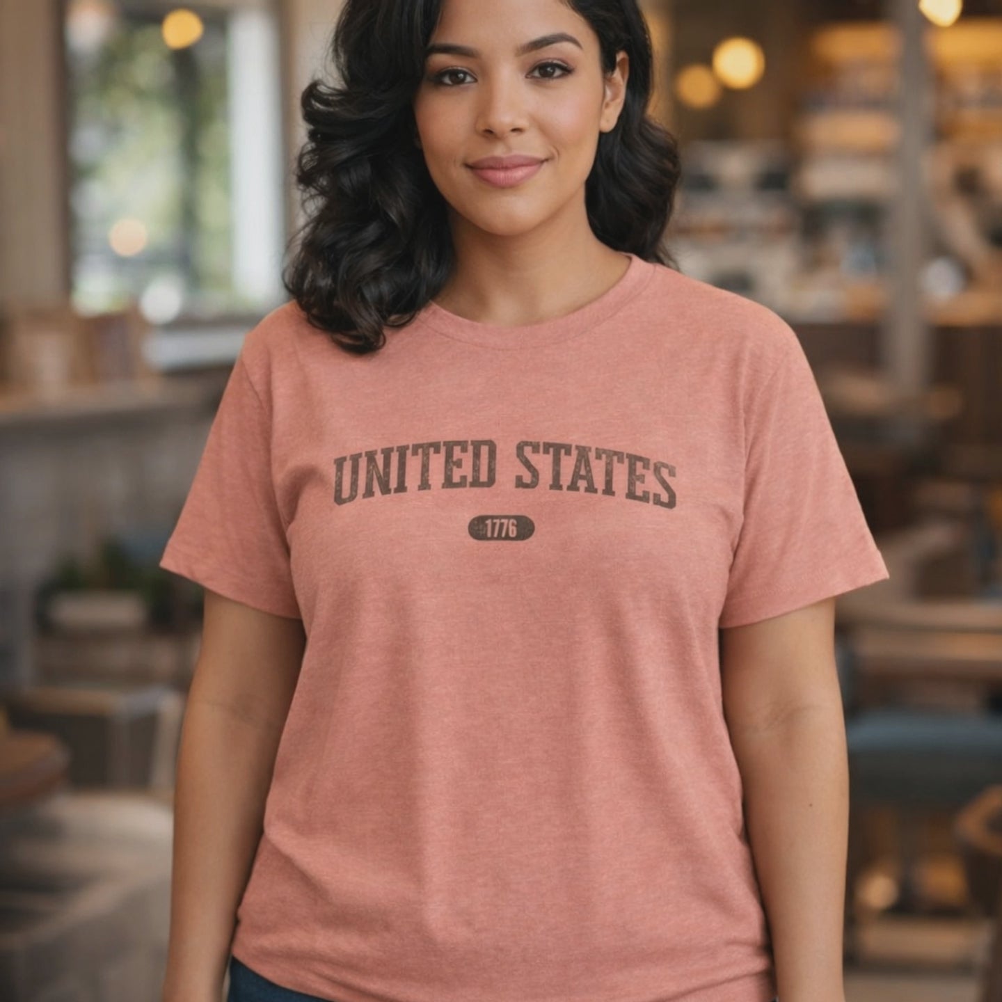 Video of a woman wearing the Heather Sunset t-shirt with 'UNITED STATES 1776' in washed brown collegiate text.